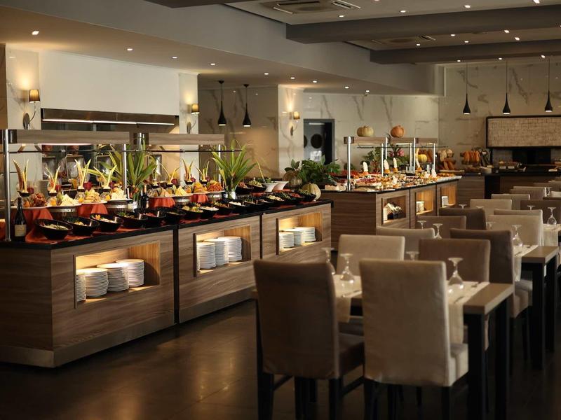 Modern hotelrestaurant buffet met tafels en diverse gerechten.