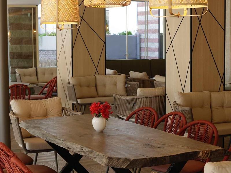 Moderne eetruimte met houten tafel, rode stoelen en gevlochten hanglampen.