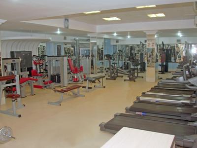 Großer Fitnessraum mit Laufbändern und Krafttrainingsgeräten in einem hellen Raum.