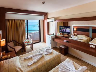 Hotelzimmer mit Meerblick, zwei Betten, Balkon und moderner Einrichtung.