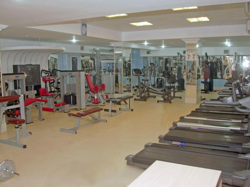 Duża siłownia z różnymi urządzeniami do ćwiczeń i bieżniami