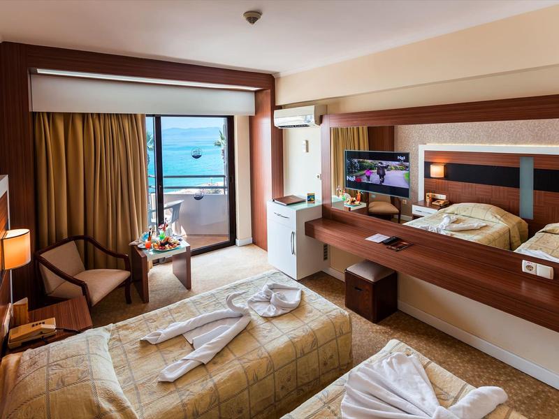 Pokój hotelowy z dwoma łóżkami, balkonem z widokiem na morze i nowoczesnymi drewnianymi meblami.