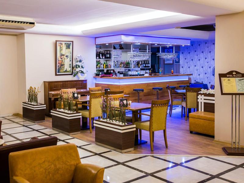Przytulny bar hotelowy z drewnianymi meblami, miejscami do siedzenia i nowoczesną atmosferą w ciepłych odcieniach.