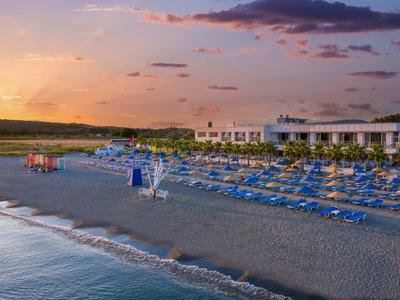 Spiaggia con lettini blu e ombrelloni al tramonto vicino all'hotel.