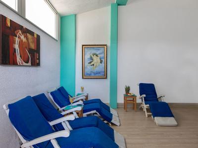 Diverse sdraio blu contro una parete bianca con opere d'arte in una stanza luminosa.