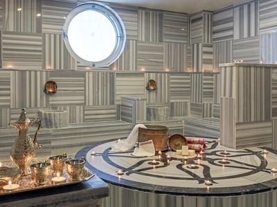 Area relax elegante con tavolo in marmo e servizio da tè in argento davanti a pareti geometriche.