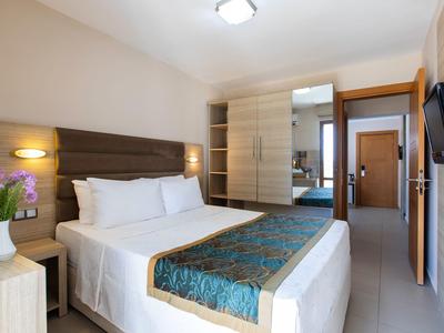 Modernes Hotelzimmer mit großem Doppelbett, Beleuchtung am Kopfteil und Flatscreen-TV