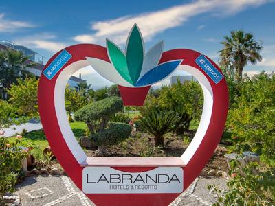 Herzförmige Farbsäule mit dem Logo von LABRANDA Hotels & Resorts in einem Garten mit Palmen
