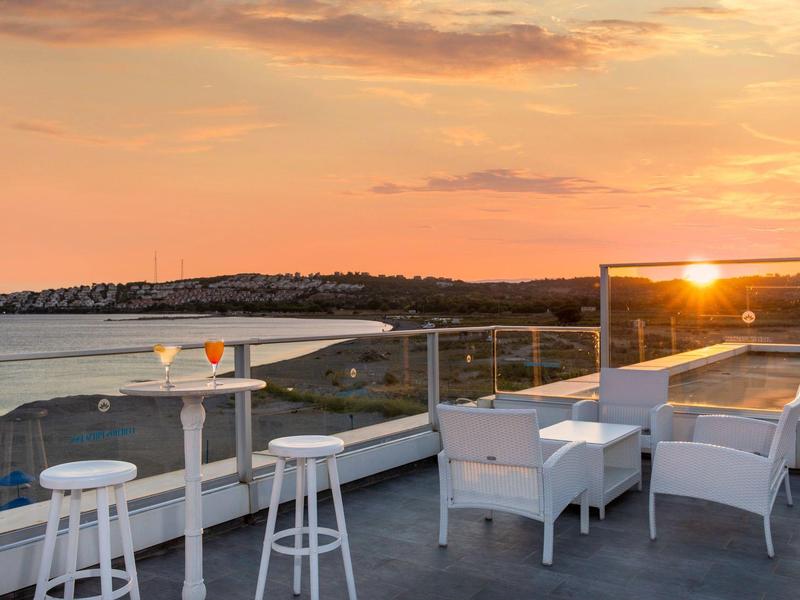 Moderna terrazza sul tetto con posti a sedere e sgabelli al tramonto vicino al mare