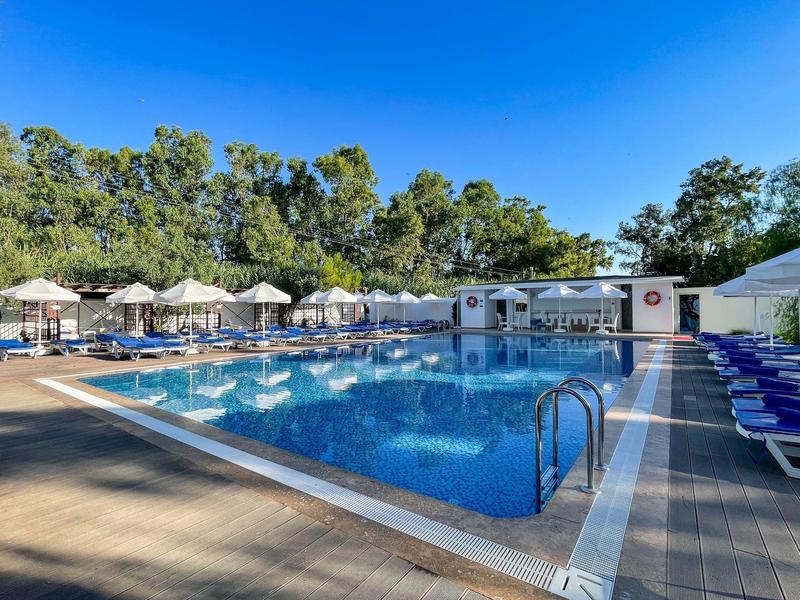 Grande piscina all'aperto accogliente con lettini e ombrelloni sotto un cielo azzurro