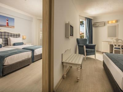 Chambre d'hôtel moderne avec lits jumeaux, fauteuil bleu et bureau blanc.