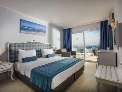 Modernes Hotelzimmer mit Doppelbett, Sitzbereich und Balkon mit Meerblick.