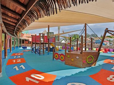 Aire de jeux colorée avec bateau et structures sous un toit en bois.