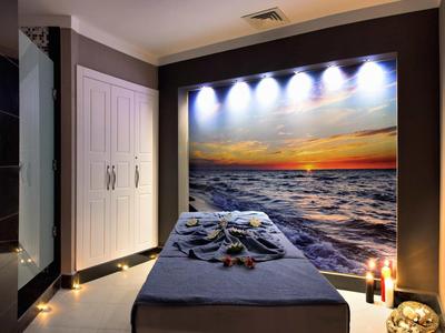Ein ruhiger Massageraum mit Meerblick Wandbild, gedämpftem Licht und entspannter Atmosphäre.