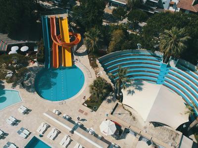 Hotelpool mit Wasserrutschen, Liegestühlen und schattigem Bereich in tropischer Umgebung.