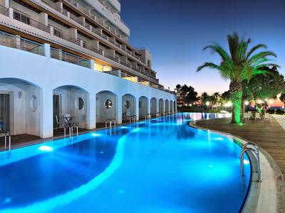 Hotel mit beleuchtetem Außenpool und Poolbar bei Nacht unter klarem Himmel.