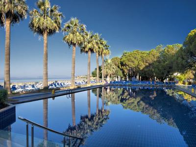 Blick auf eine beleuchtete Küstenstadt bei Nacht mit Berg im Hintergrund und ruhigem Wasser.