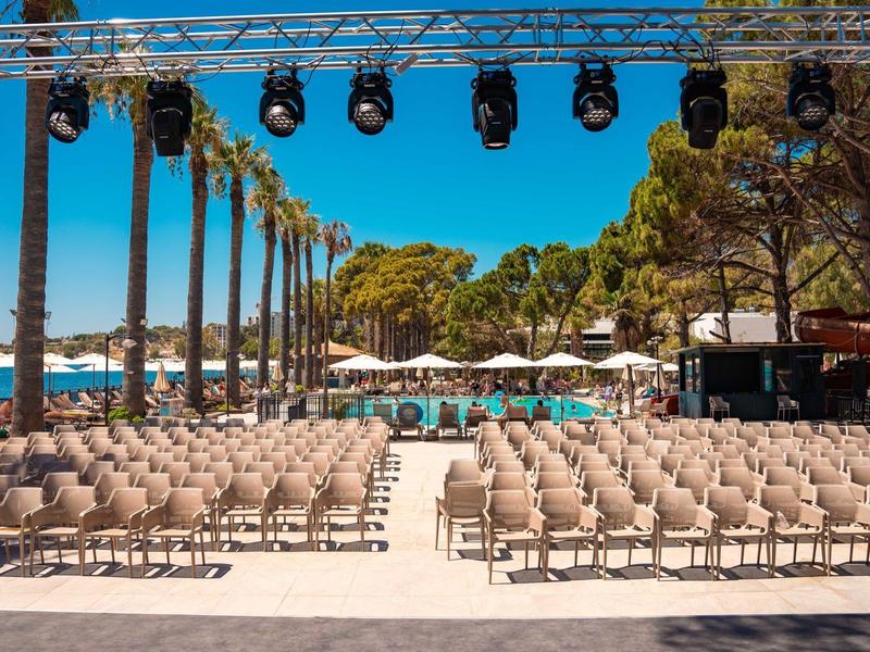 Przestrzeń na zewnątrz z rzędami krzeseł, palmami i niebieskim niebem, idealna na wydarzenia hotelowe.