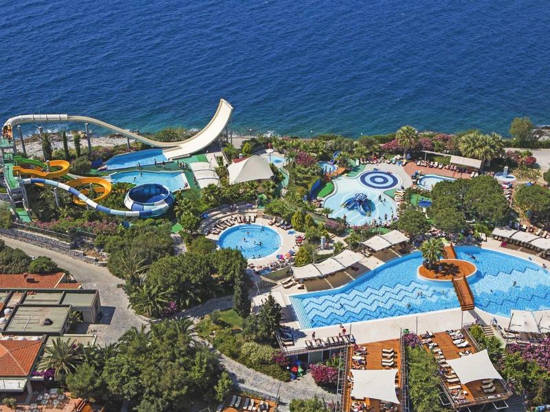 Water park with multiple pools, water slides, and a view of the sea