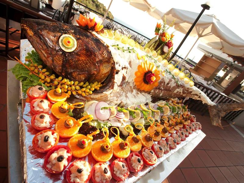 Festive buffet with various hors d'oeuvres and a large meat piece in an outdoor hotel setting.