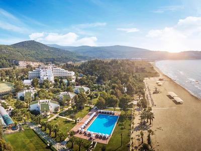 Letecký pohled na hotelový komplex s bazénem u dlouhé písečné pláže a moře.