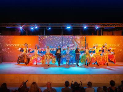 Tänzerinnen in bunten Kleidern auf einer Bühne bei einer Abendvorstellung