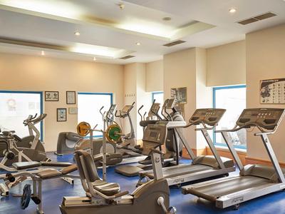 Moderner Fitnessraum mit Laufbändern, Trainingsgeräten und großen Fenstern.