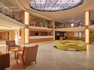 Prostorná hotelová hala s moderním posezením a přirozeným světlem.