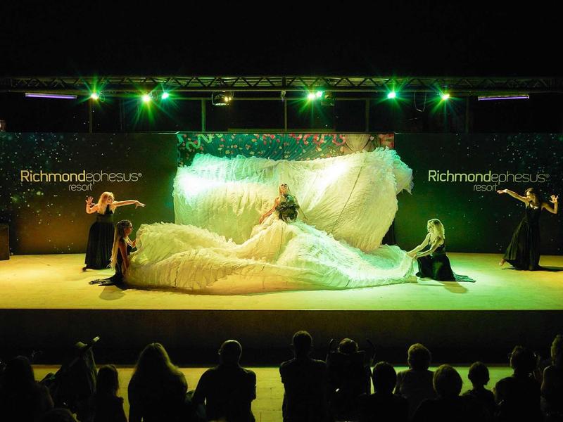 Představení na scéně s impozantní bílou šatou a zeleným osvětlením.