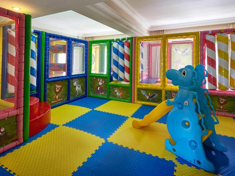 Barevná herna s pěnovou podlahou a modrou drakovou strukturou pro děti.