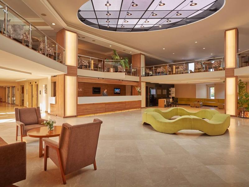 Prostorná hotelová hala s moderním posezením a přirozeným světlem.