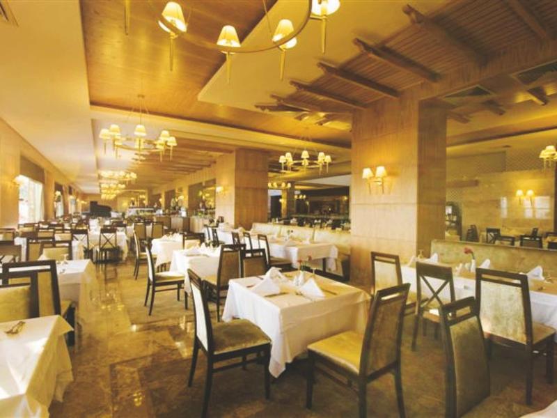 Großes, elegantes Restaurant mit weißen Tischdecken, Holzstühlen und warmem Deckenlicht.