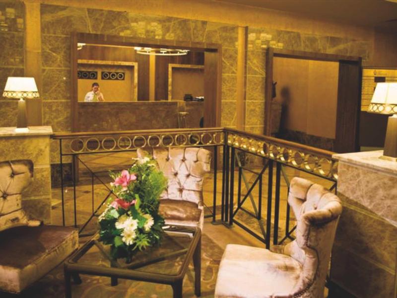 Gemütliche Sitzecke mit gepolsterten Stühlen, Blumenarrangement und warmem Licht in steinernem Raum.