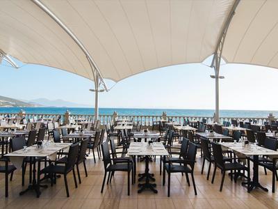 Outdoor restaurant with sea view and white canopies over the tables.