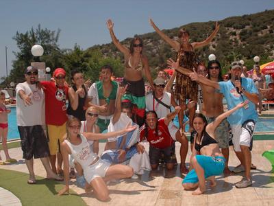 Gruppe von Menschen posiert fröhlich am Pool mit Hügeln im Hintergrund.