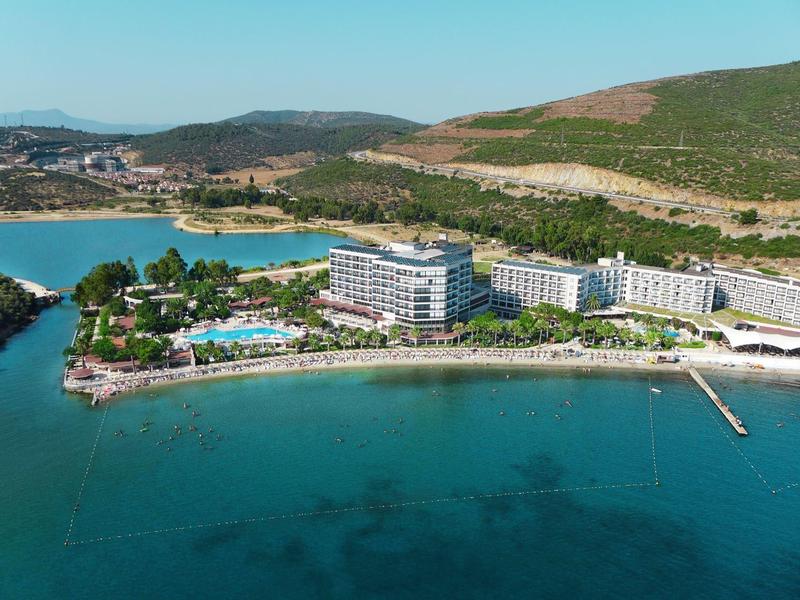 Hotel complex with large pool and sea view at a sunny beach.