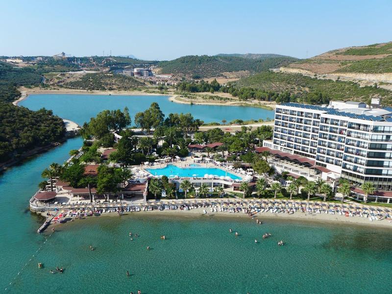 Hotel on the riverside with pool, sun loungers, and surrounding green landscape.