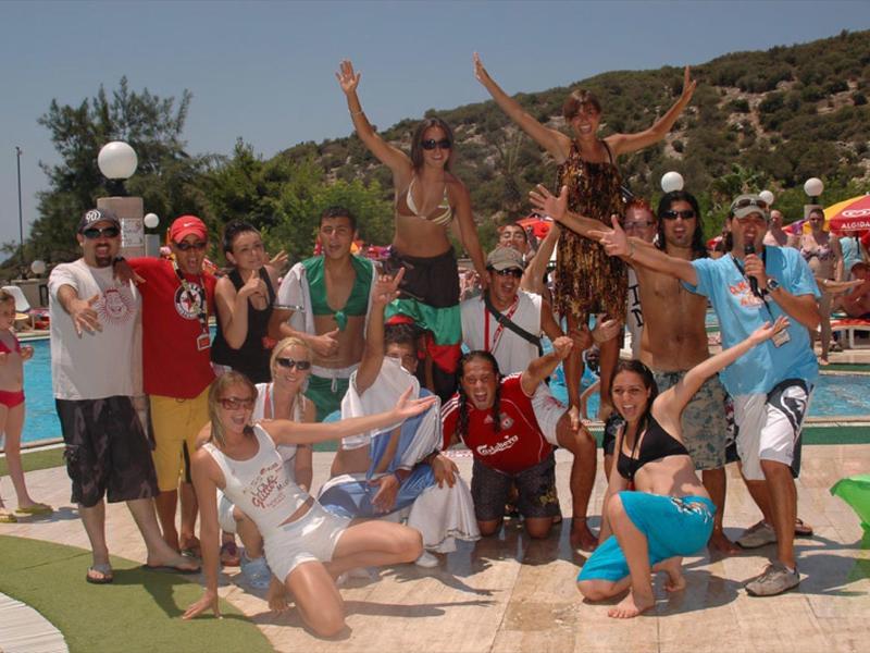 Group of people happily posing beside a pool on a sunny day.
