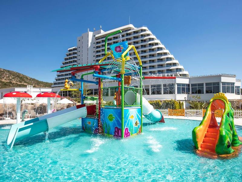 Hotel pool with colorful water playground and slides under clear blue sky