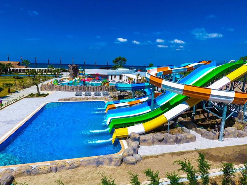 Large outdoor pool with colorful water slides on a sunny day at a vacation spot.