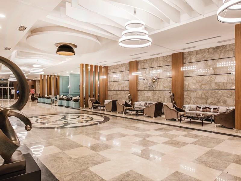 Spacious hotel lobby with modern art, leather chairs, and marble flooring.