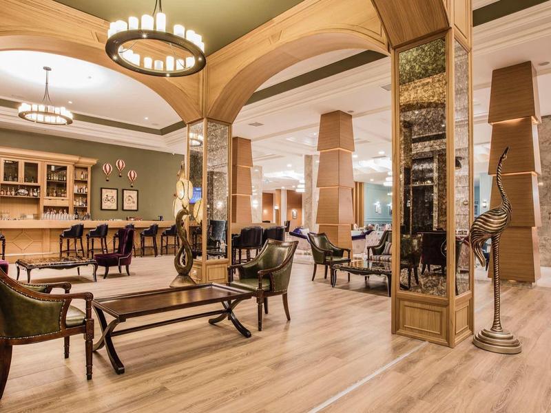 Elegant hotel lounge area with wooden floors, stylish armchairs, and large chandelier.