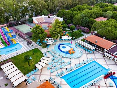 Buntes Freizeitzentrum mit mehreren Schwimmbecken, Wasserrutschen und grüner Umgebung.