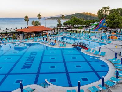 Gran piscina con toboganes de agua y tumbonas en un complejo hotelero junto al mar.