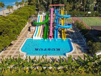 Piscina con toboganes coloridos y zona de césped en un resort tropical junto a la playa