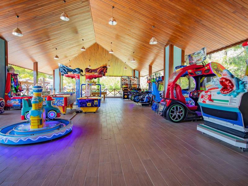 Gran área de juegos interior con juguetes coloridos y techo de madera en un hotel.