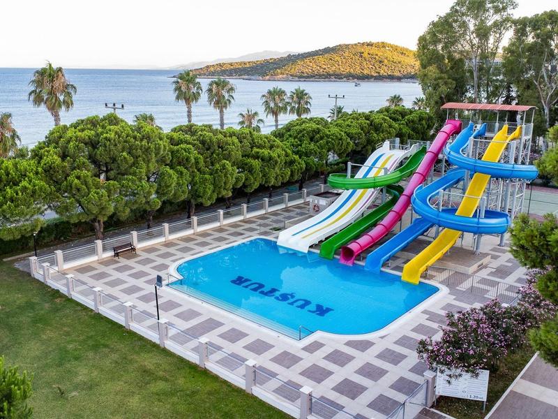 Parque acuático con varios toboganes de agua frente al mar y árboles en un hotel.