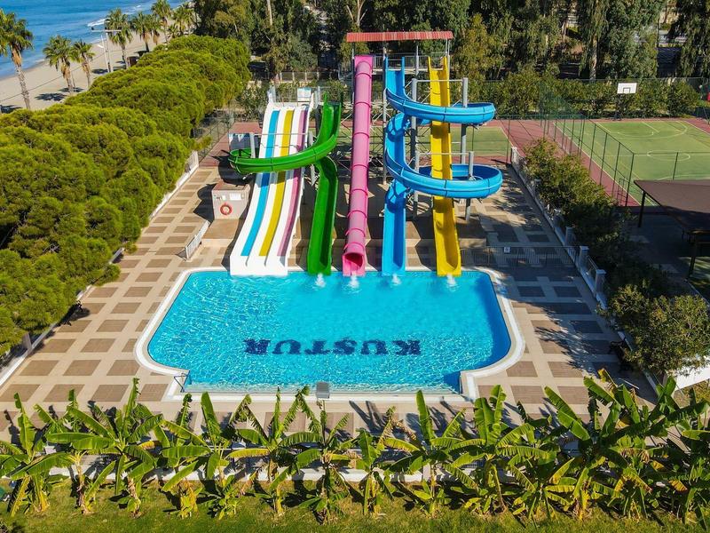 Piscina con toboganes coloridos y zona de césped en un resort tropical junto a la playa