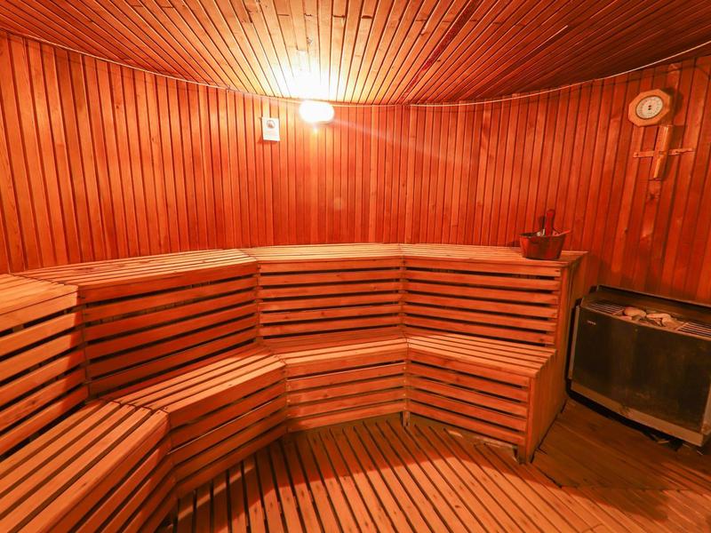 Sauna de madera con bancos en ángulo y calentador en una esquina