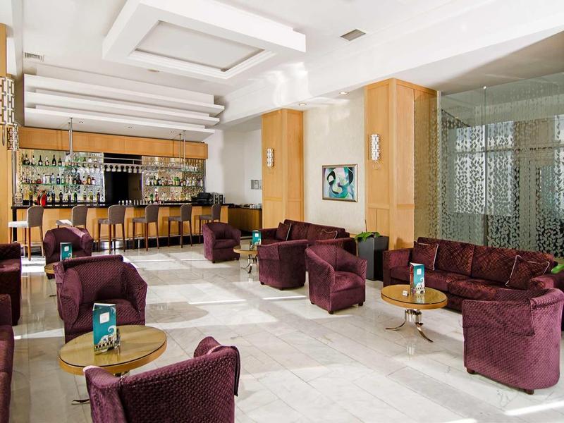 Heller Loungebereich mit lila Sesseln, Holzvertäfelungen und weißen Marmorböden.